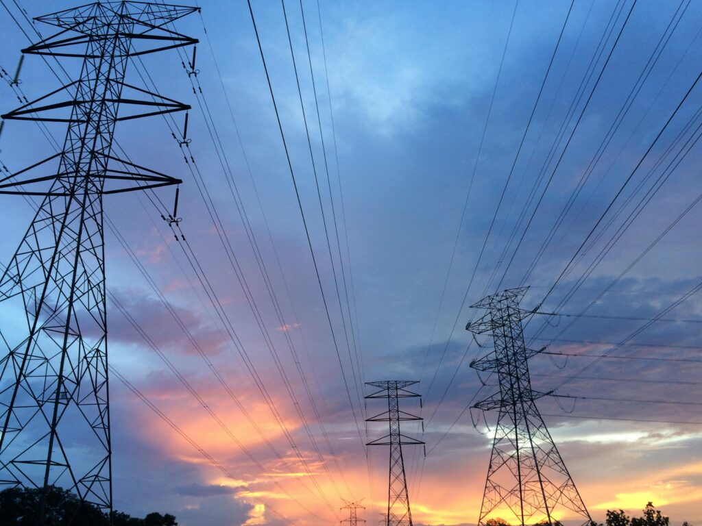 pexels-photo-189524-189524 A scenic view of high voltage power lines silhouetted against a vibrant sunset sky.